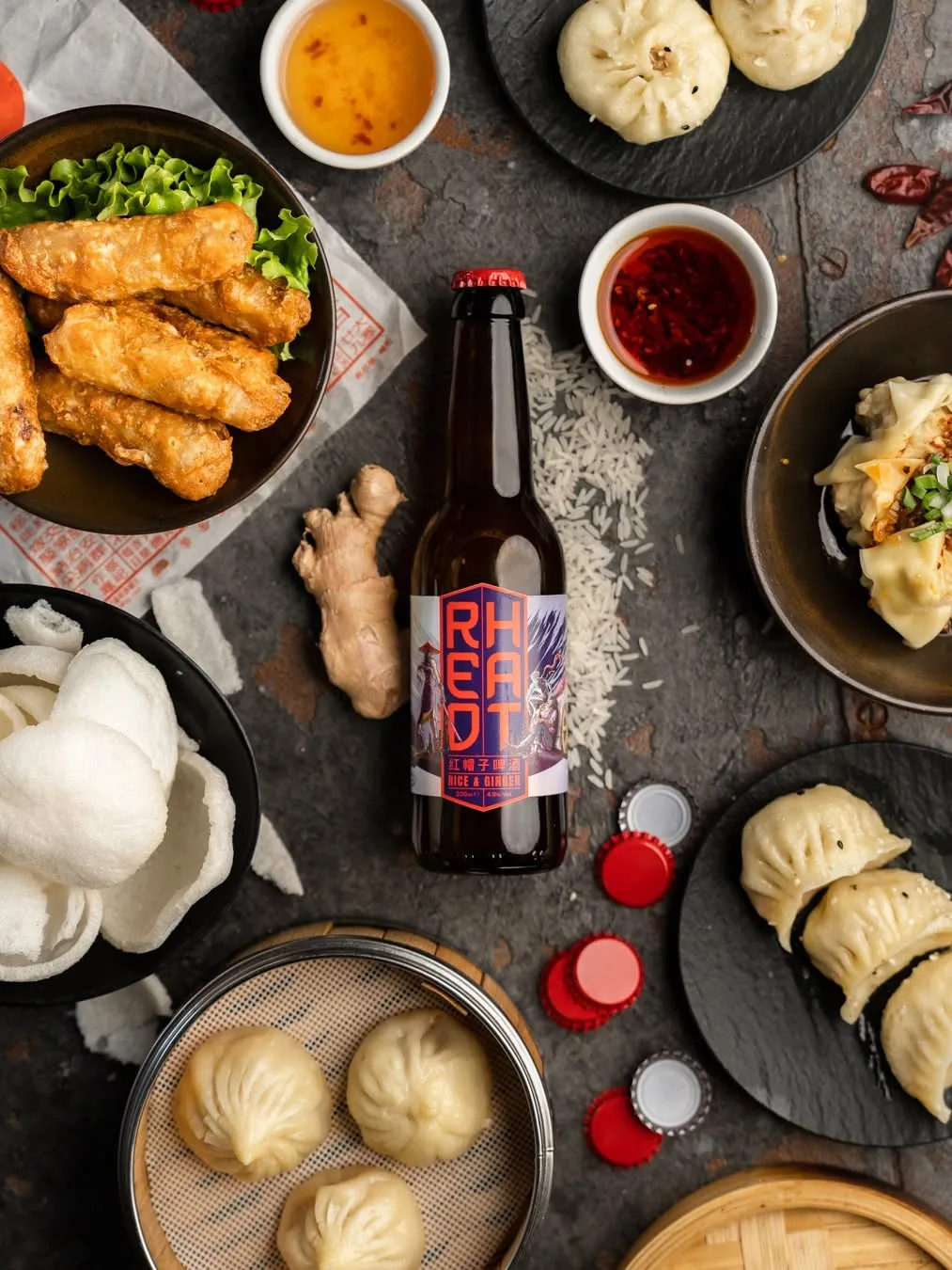 Dumplings, bao and a bottle of beer laid out on a dark table, shot for Laotse